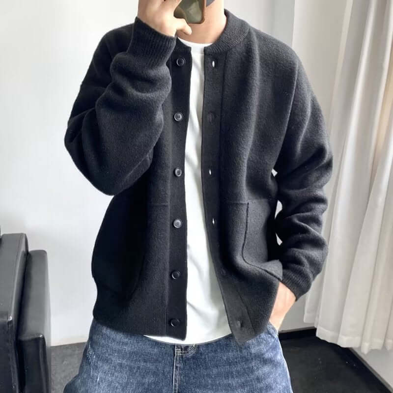 Man wearing a stylish black cardigan over a white shirt and jeans, showcasing modern fashion for a versatile look.