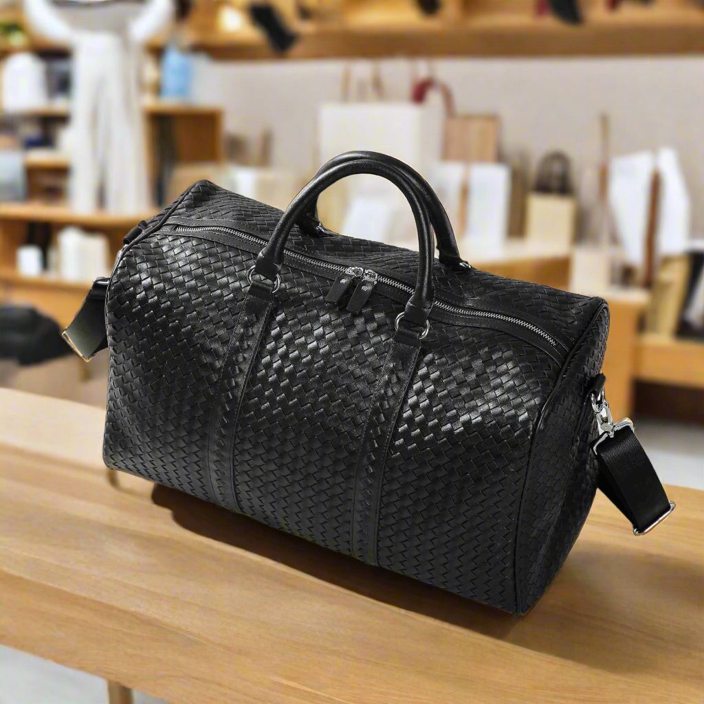 Elegant black Kamau travel bag with textured design and sturdy handles, perfect for organized and stylish journeys.