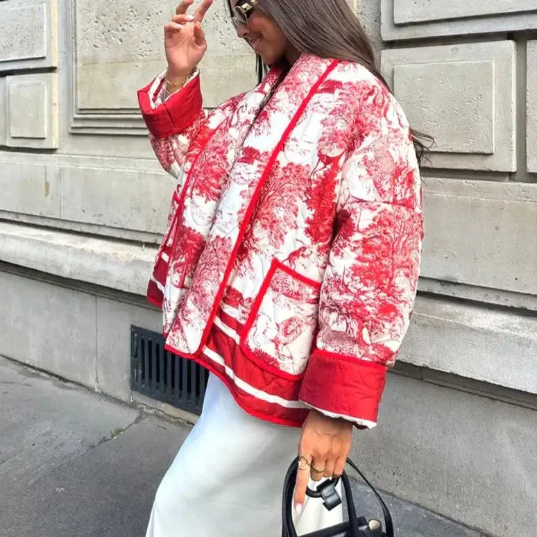 Woman wearing a stylish red and white Swannie jacket with intricate design, perfect for fall, walking outdoors.